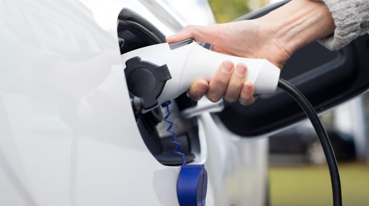 Frau lädt ein Elektrofahrzeug auf