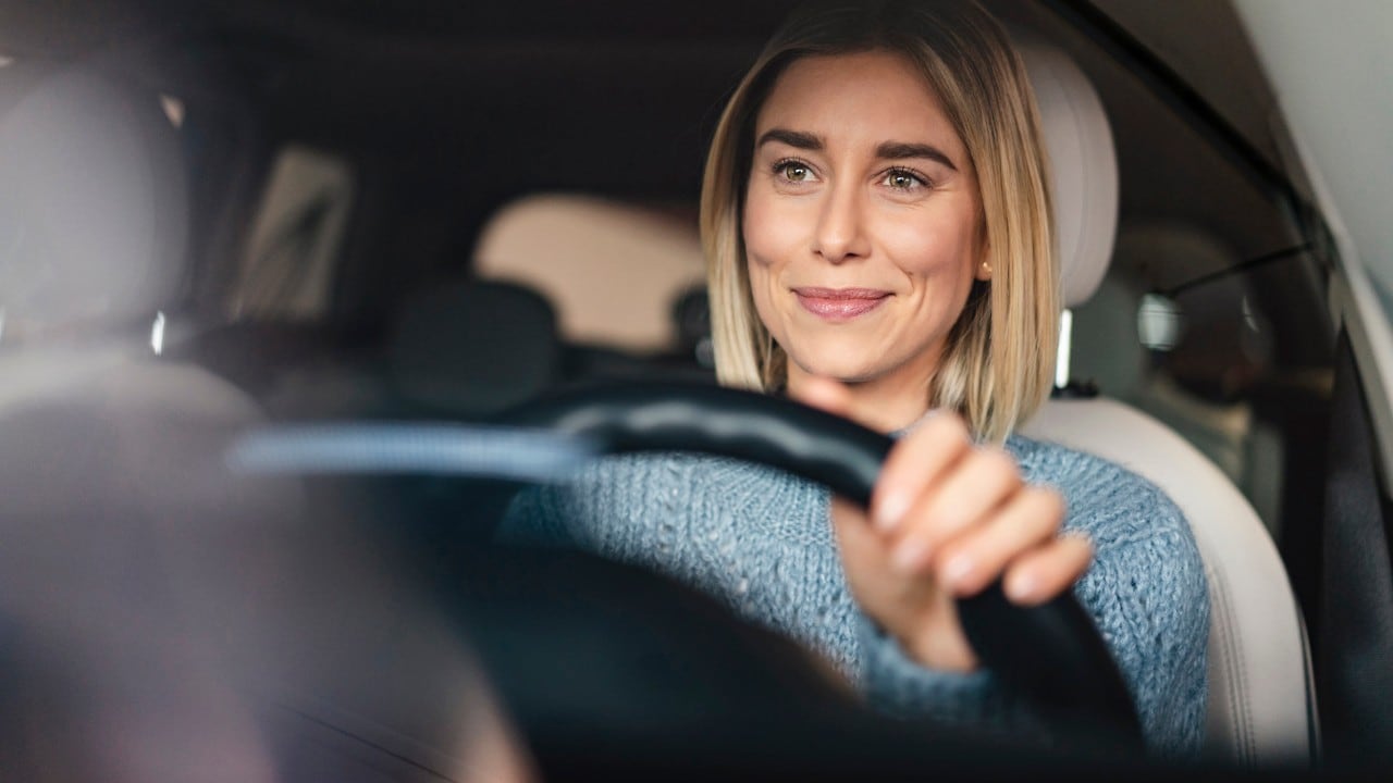 Portrait of smiling young woman driving a car