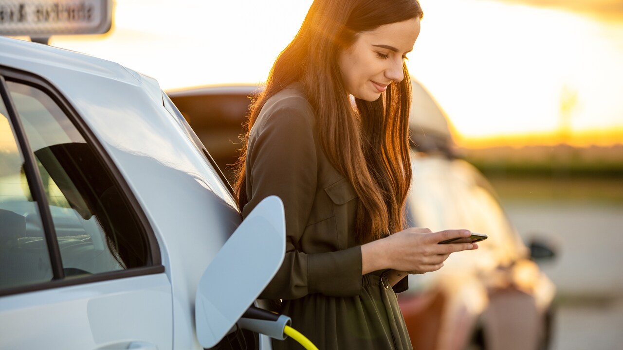 Frau lädt entspannt ein Elektroauto auf.