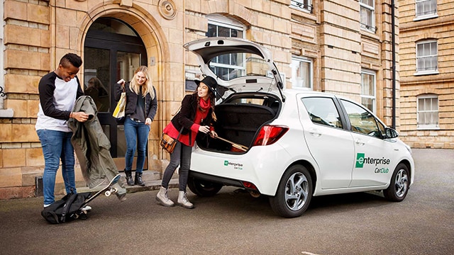 Leute, die ihr Gepäck in ein kleines weißes Auto werfen 