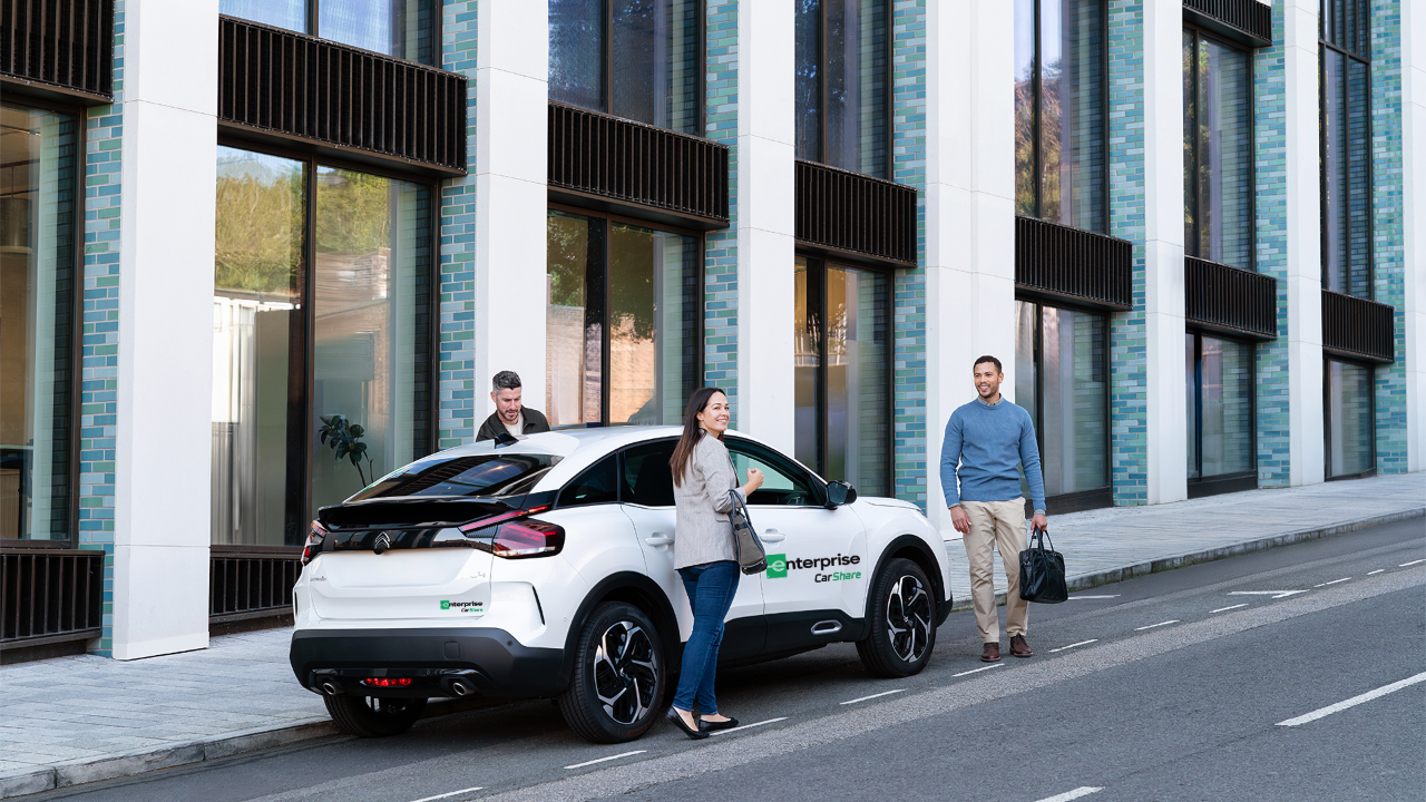 Drei Personen steigen in modernes Carsharing-Auto