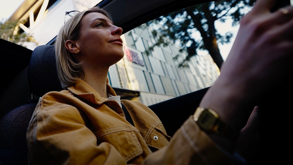 Frau in einer gelben Jacke, die ein Auto fährt.