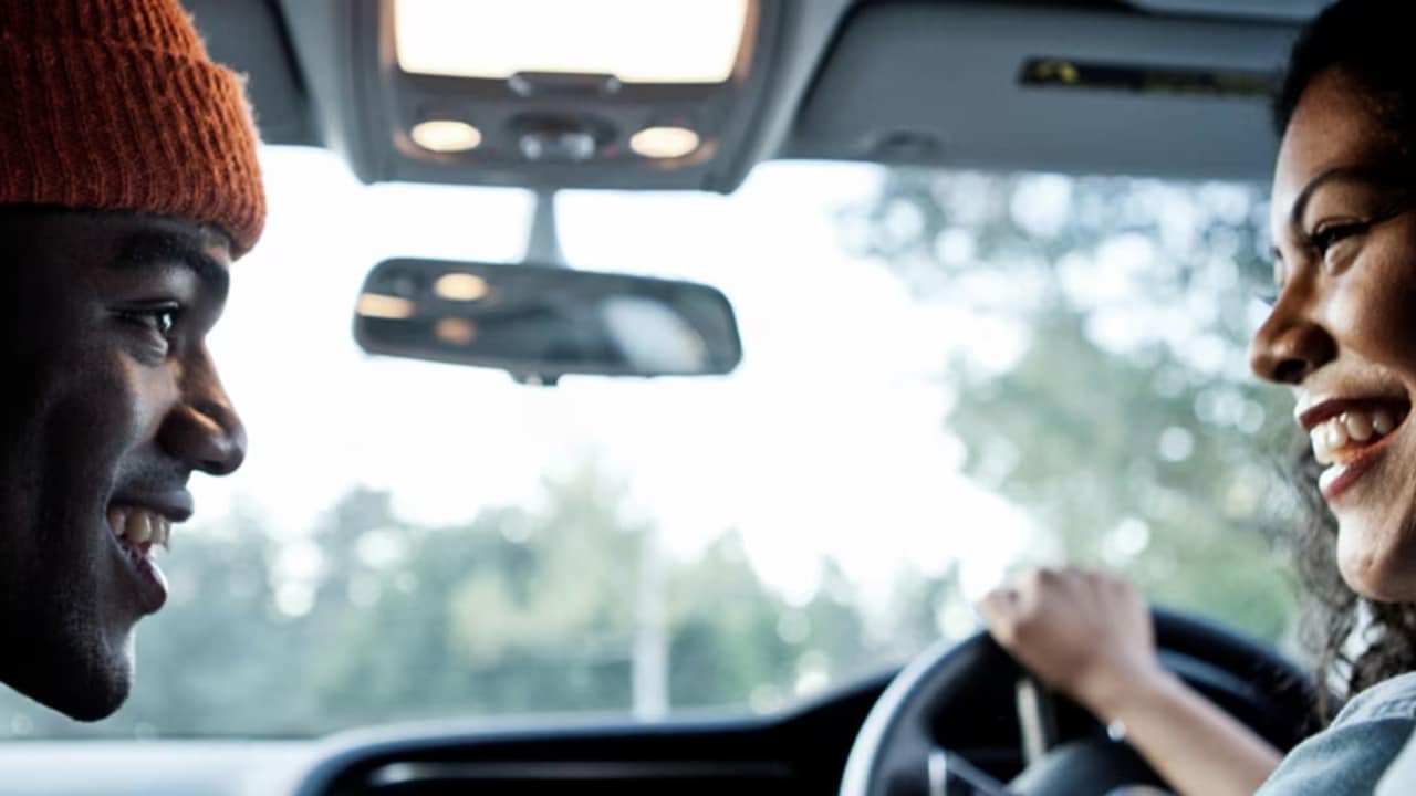 Nahaufnahme eines Mannes und einer Frau, die in einem Auto sprechen.