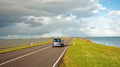 Car driving along a flat road by the sea